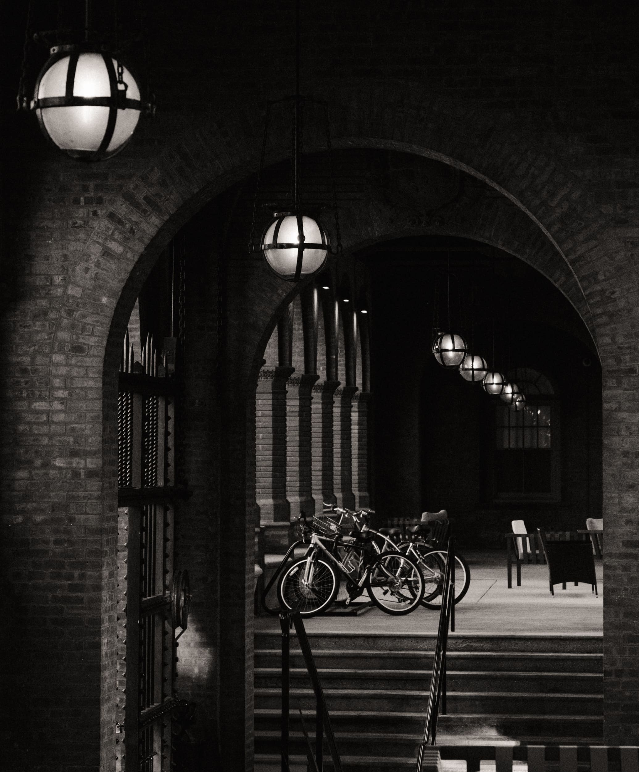 Black and white architectural photo of Flagler College's brick archways and hanging lanterns at night