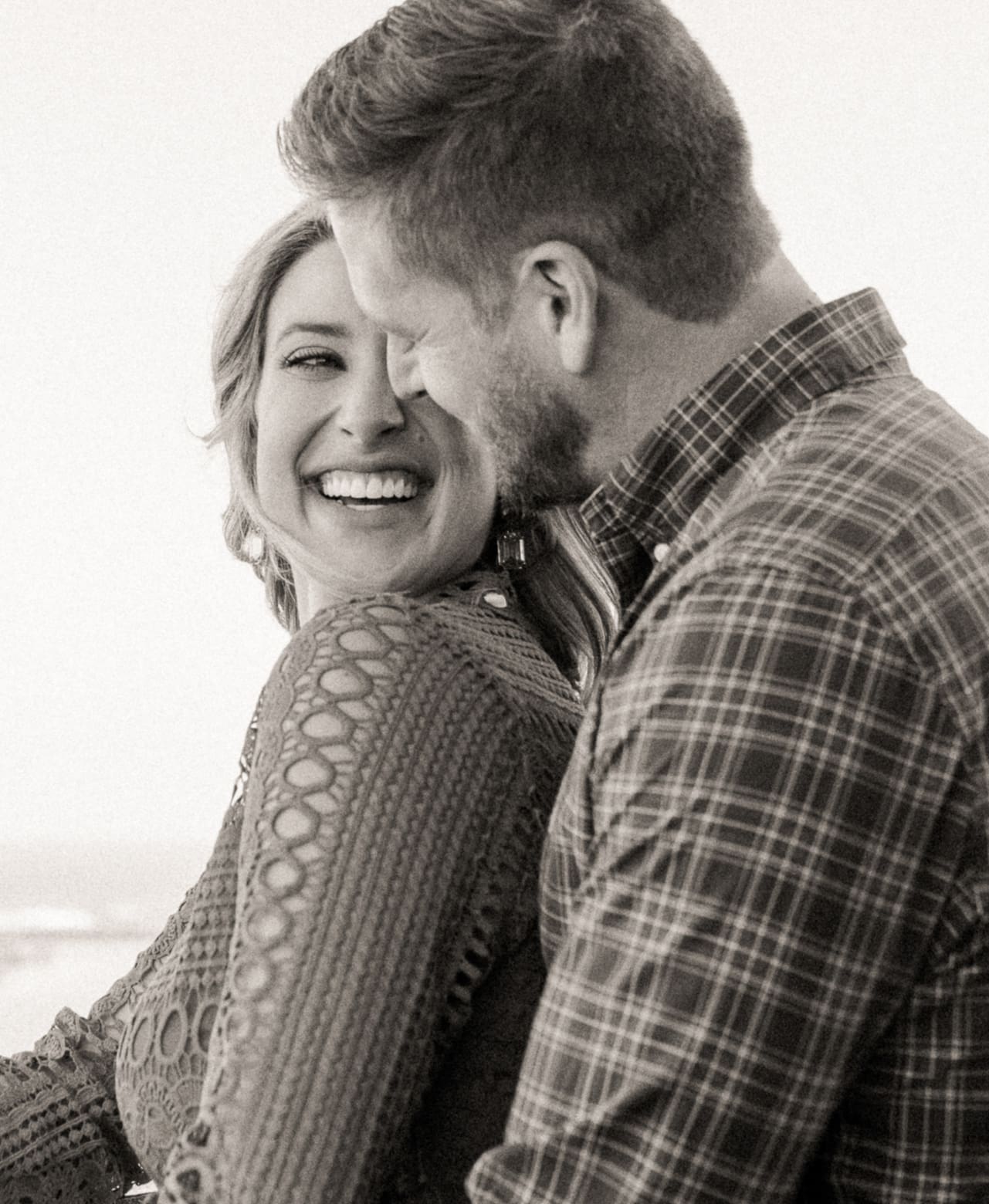 Black and white photo of a laughing woman hugged by her fiancé during their St. Augustine engagement session