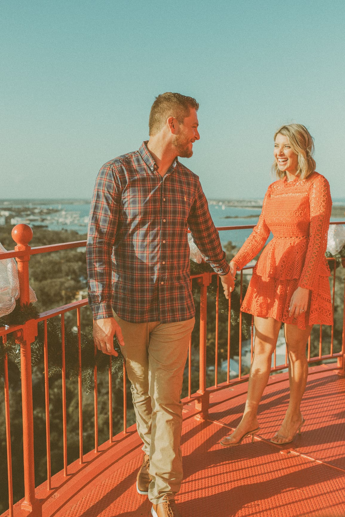 Couple holding hands and laughing in sunset light at the top of the St. Augustine Lighthouse