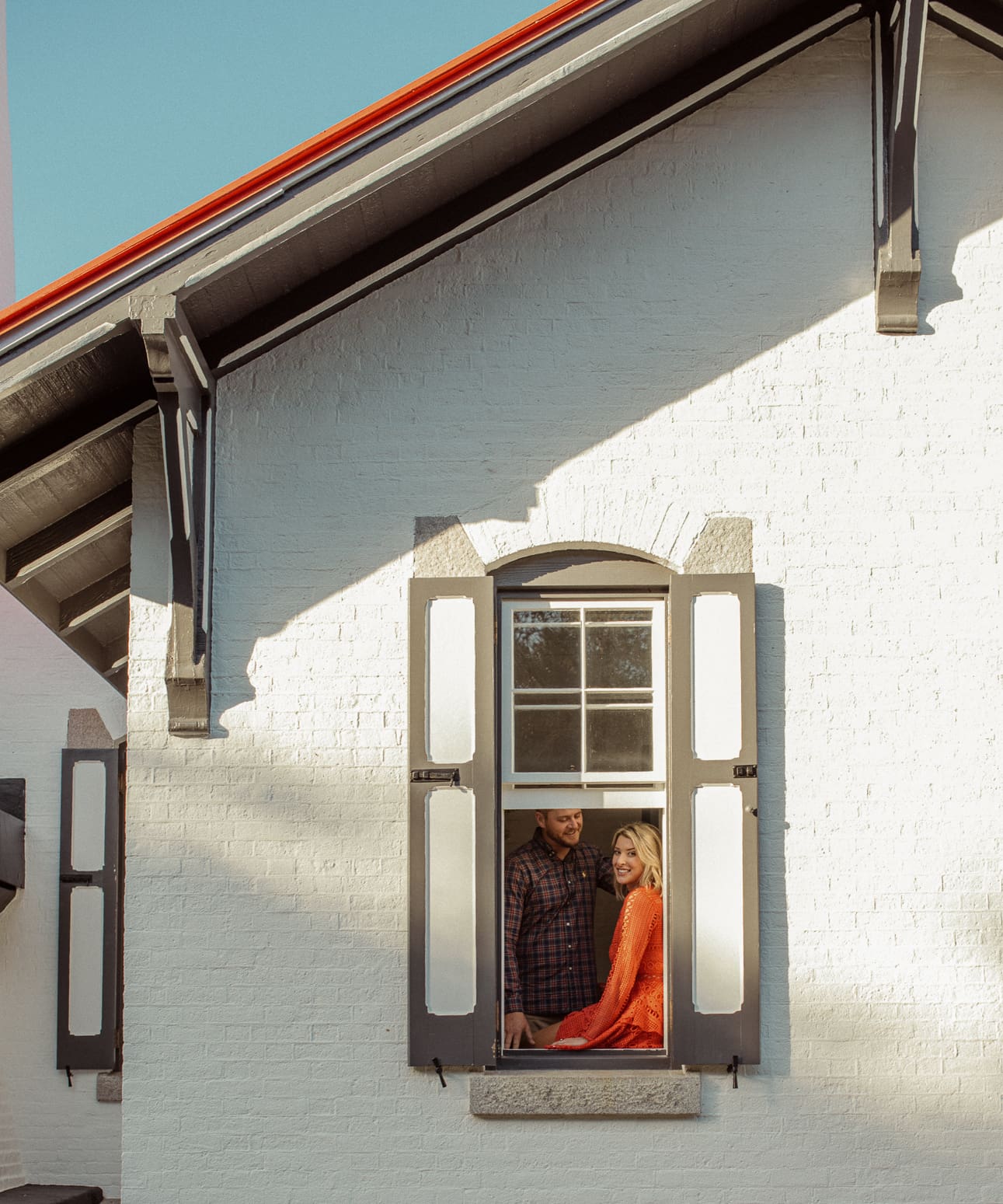 Engaged couple framed in a shuttered window of the keeper's house at the St. Augustine Lighthouse