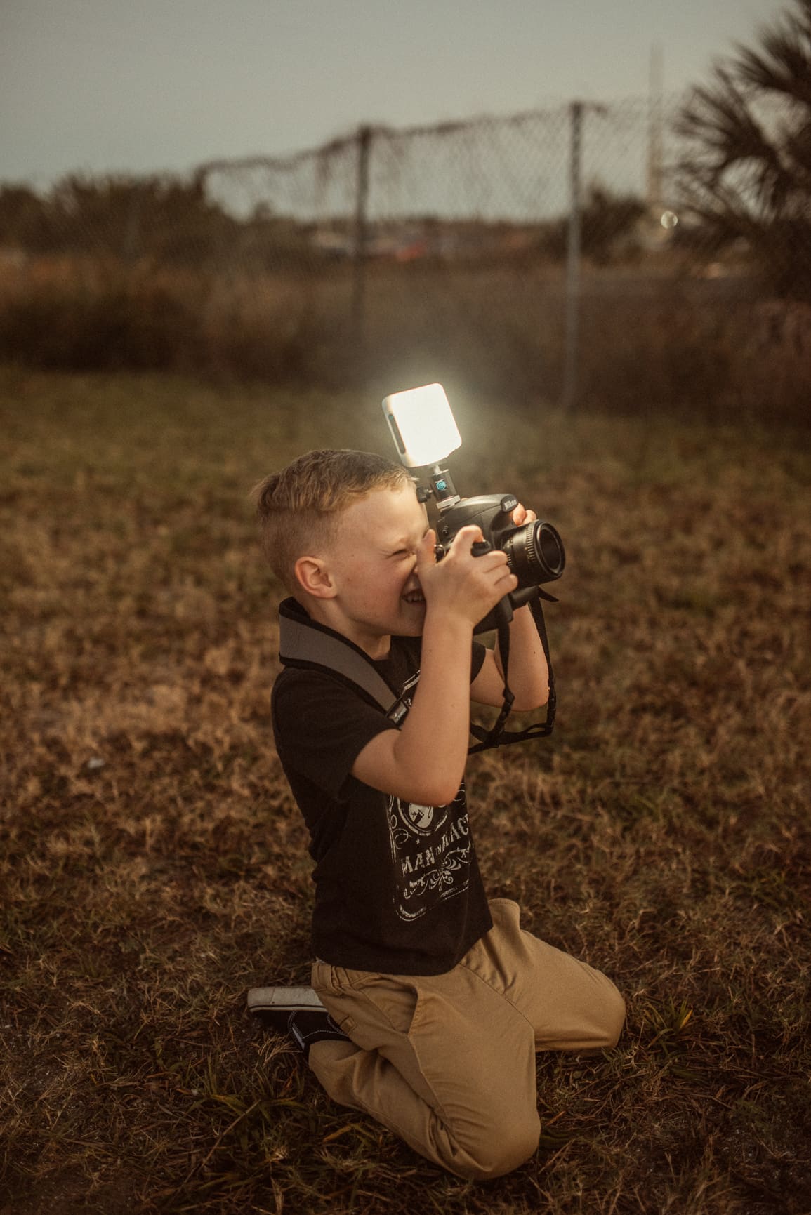 Young boy kneeling in the grass with a camera during a St. Augustine family engagement session