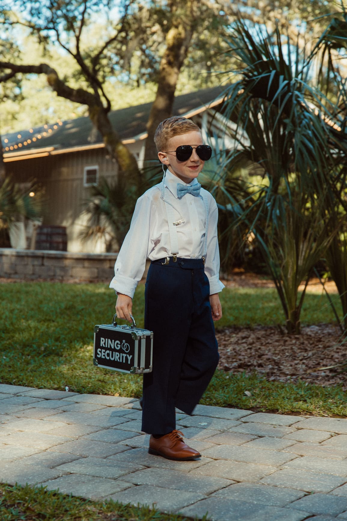 Ring bearer walking with a "Ring Security" briefcase and sunglasses. 