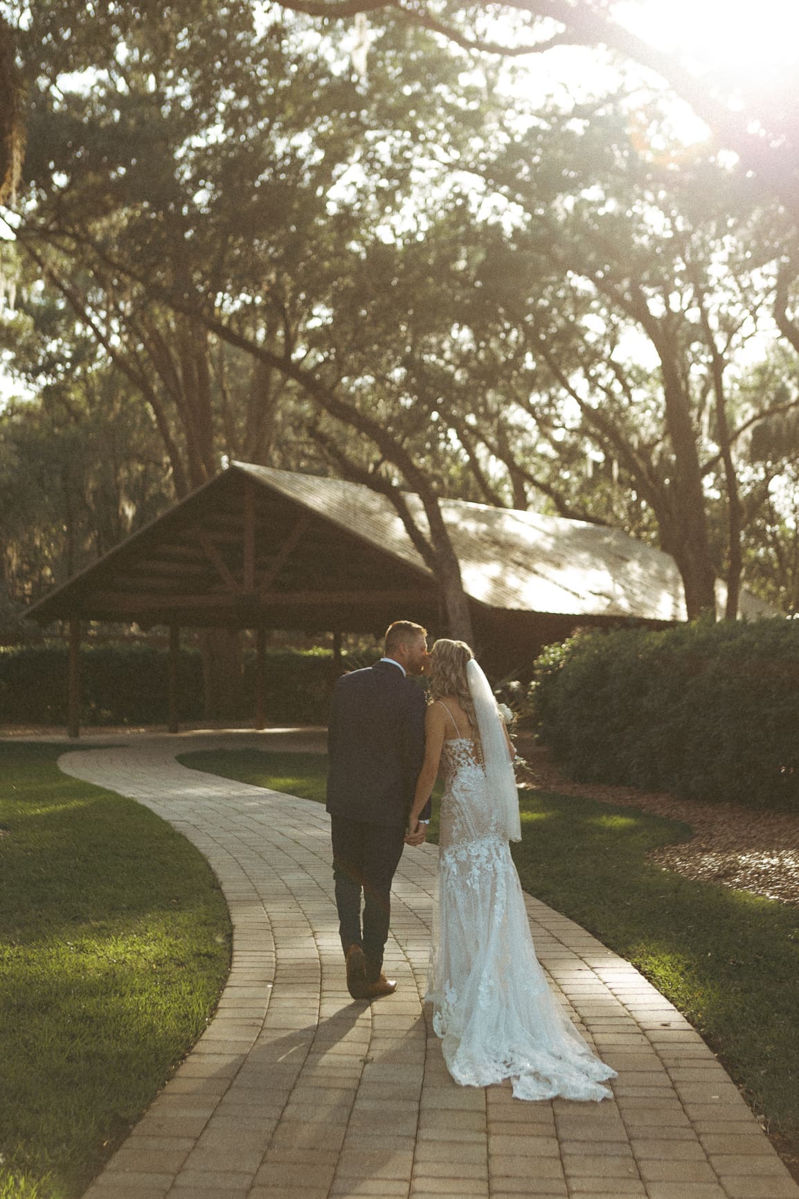Bride and groom kissing while walking hand in hand at their Bowing Oaks wedding.