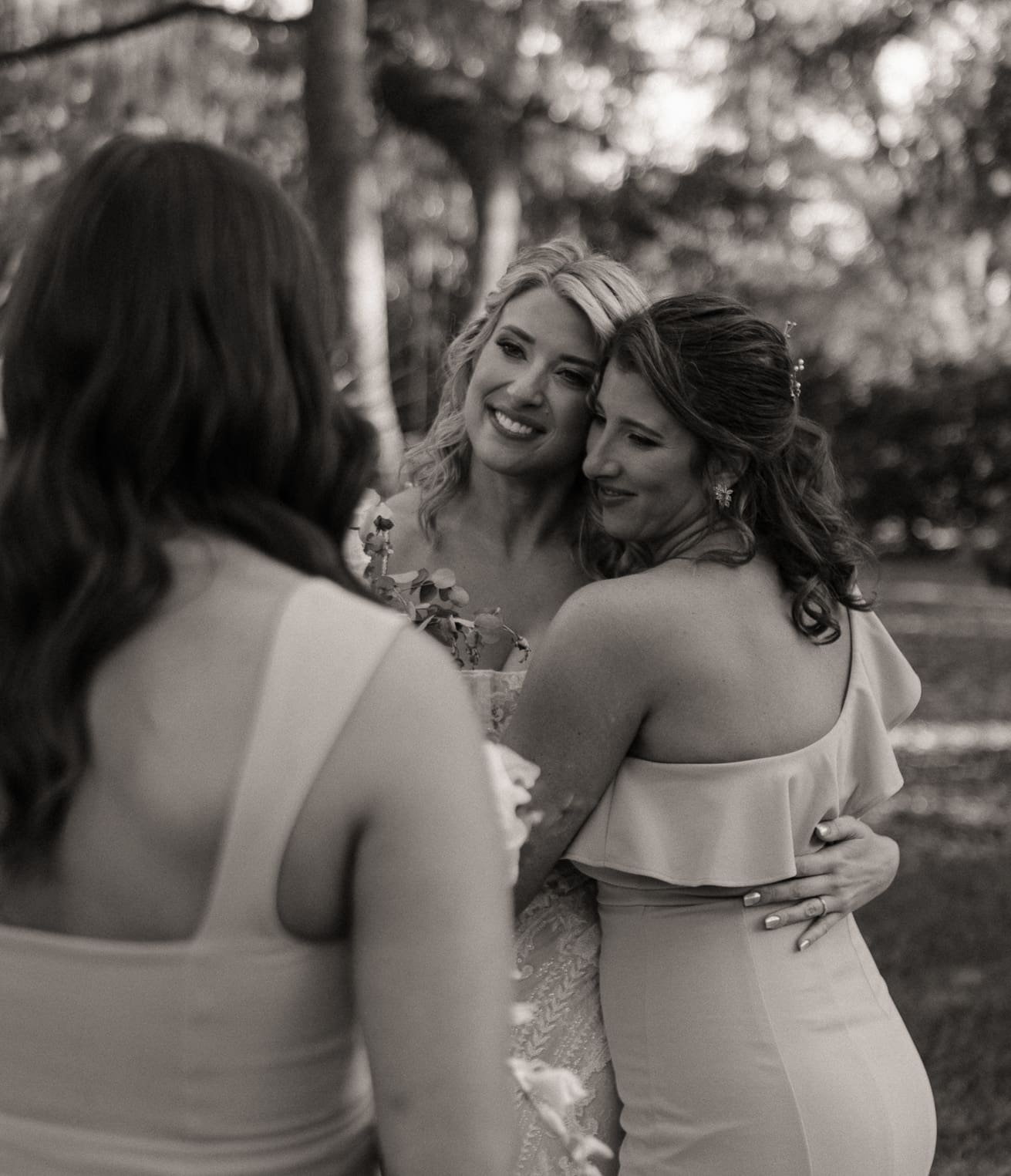 Bride sharing an emotional embrace with bridesmaid after the ceremony.