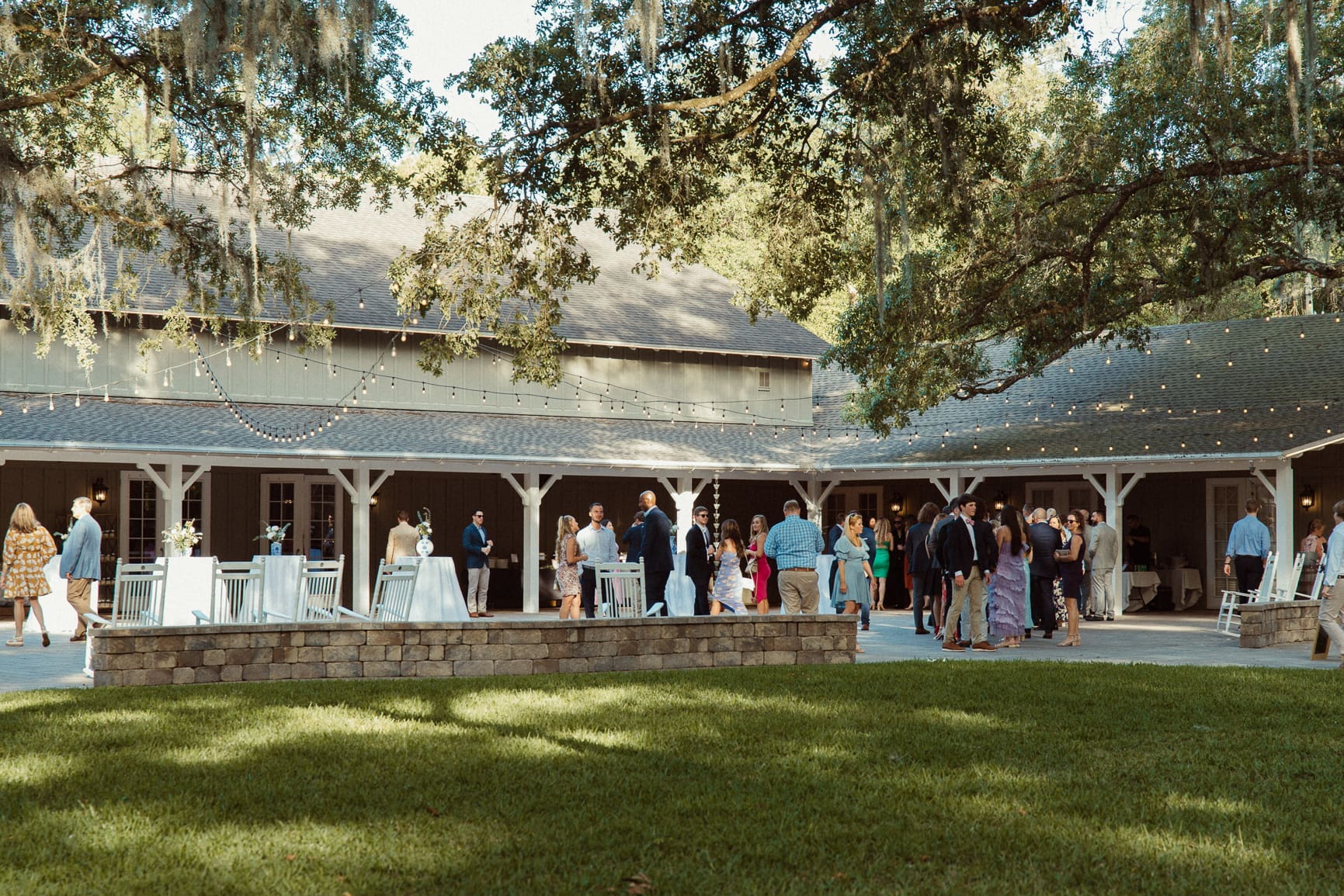 Wedding guests mingling under the string-lit pavilion at Bowing Oaks reception. 