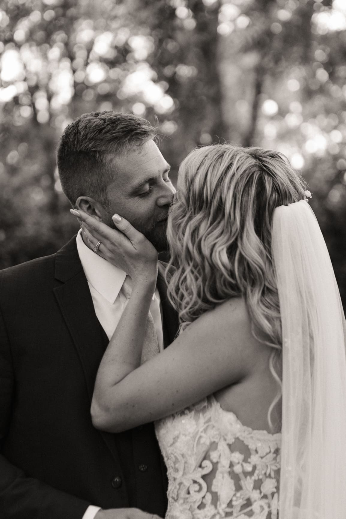 Groom cradling bride's face in a tender embrace during portraits. 
