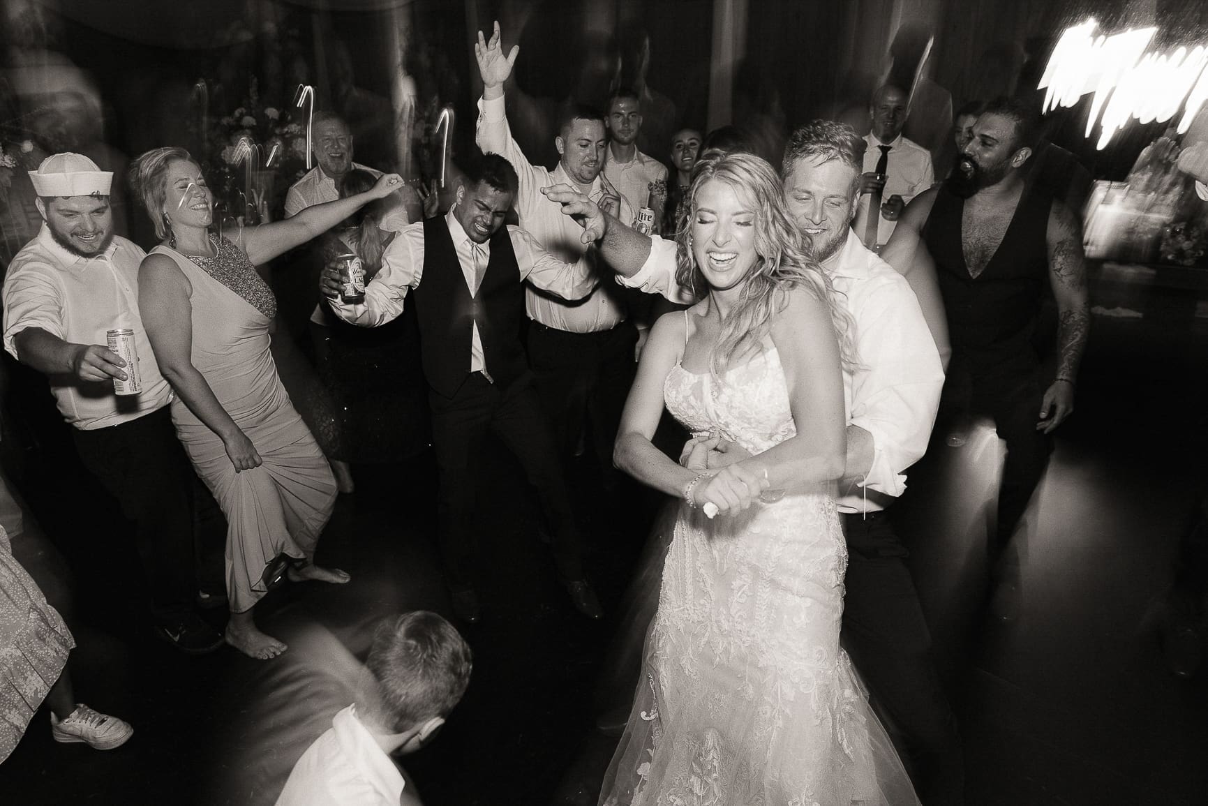 Bride and groom dancing together as guests cheer them on.