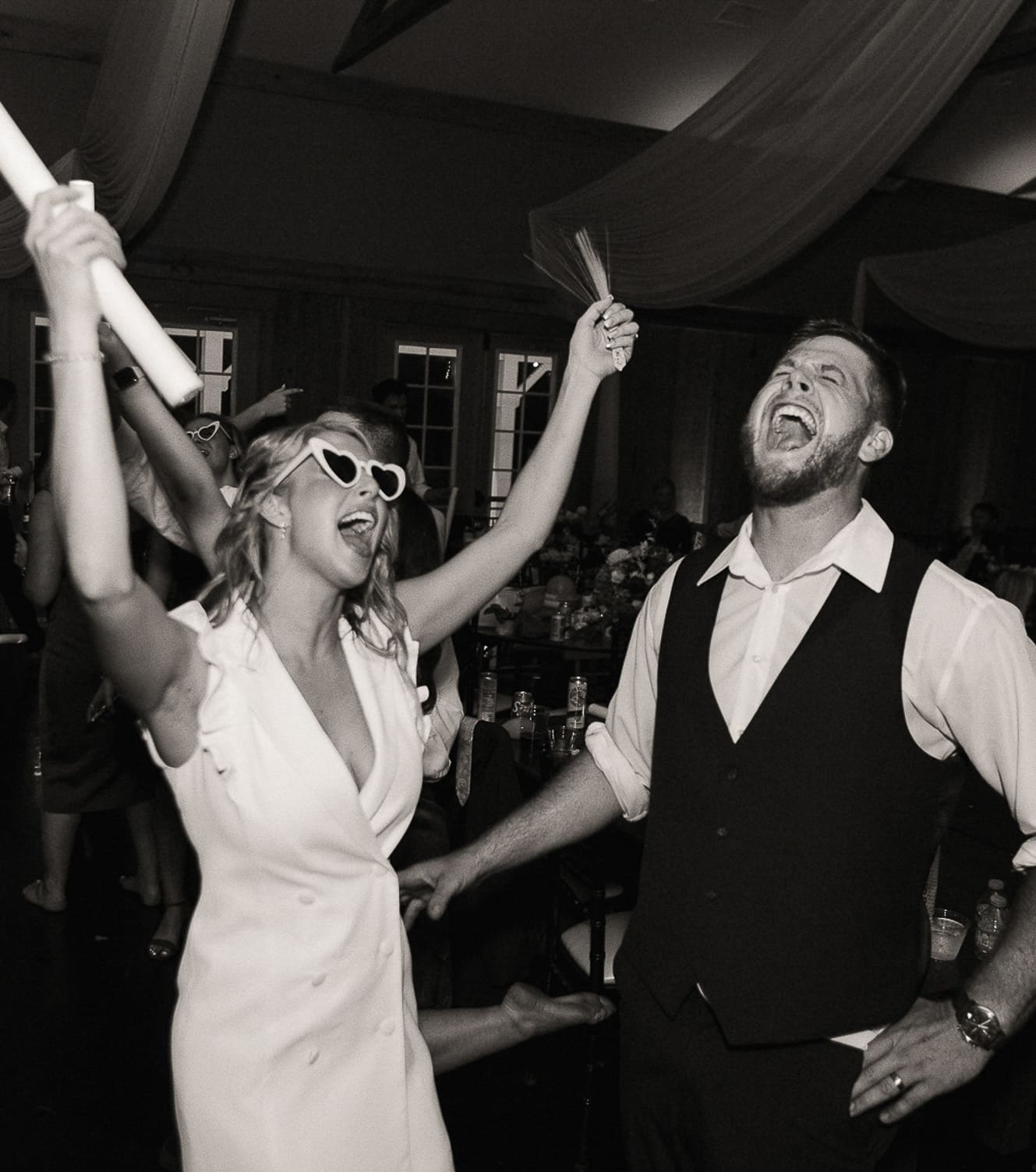 Bride and groom celebrate on dance floor during fun and loud reception party. 