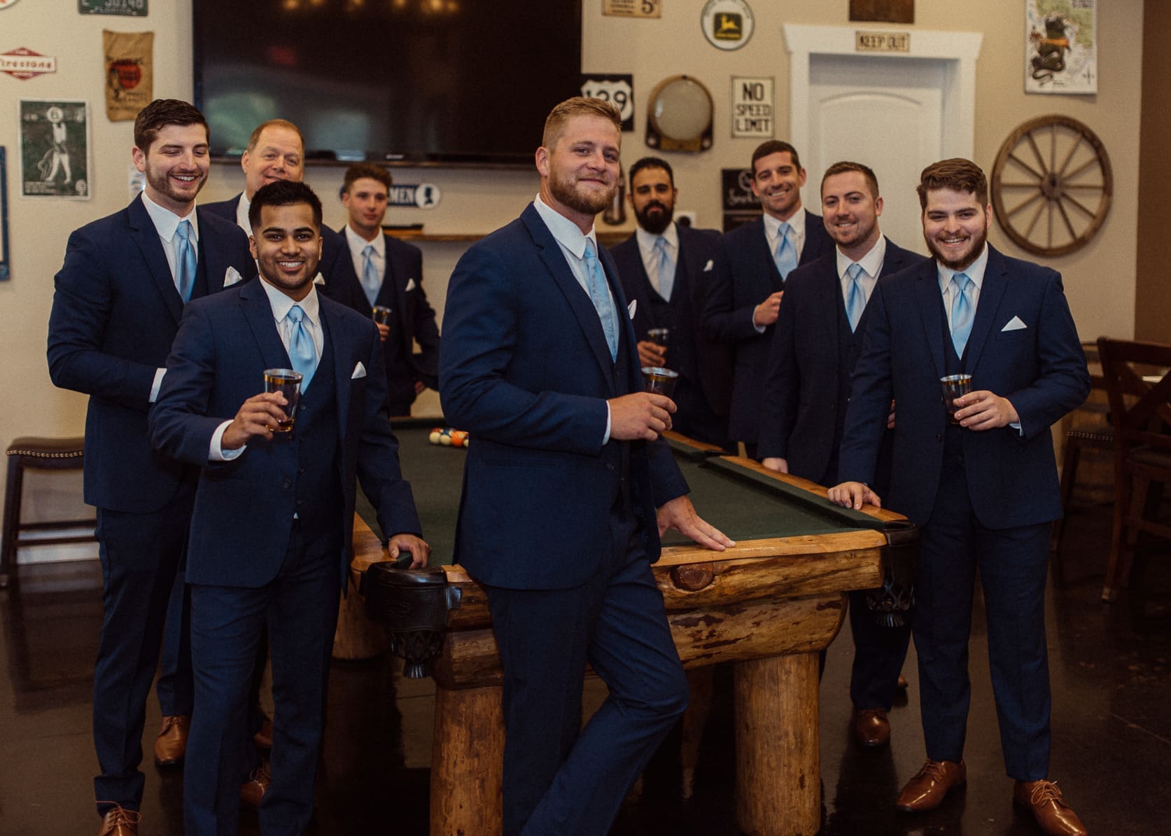 Groom toasting with groomsmen and a pool table before the wedding. 
