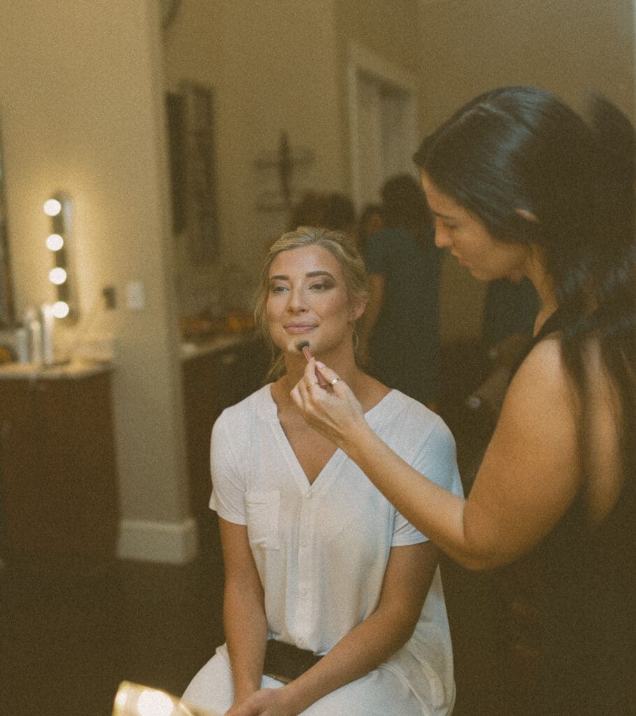 Bride having her makeup applied during wedding morning prep. 