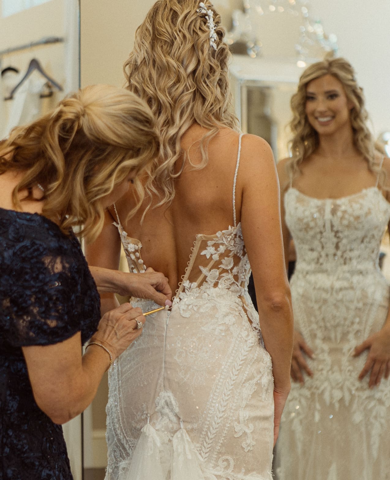 Bride having her wedding dress fastened before the ceremony at Bowing Oaks. 