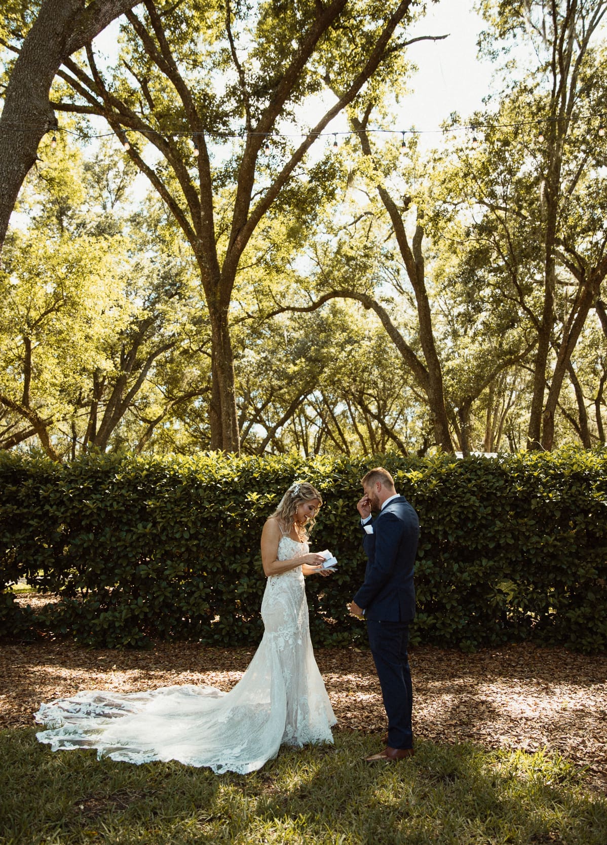 Bride and groom reading their private vows to each other beneath the trees at Bowing Oaks.