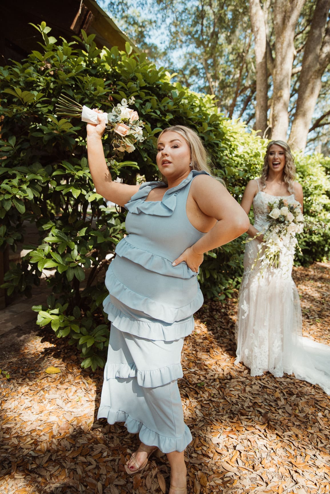 Bridesmaid in a candid playful moment with the bride in the background. 