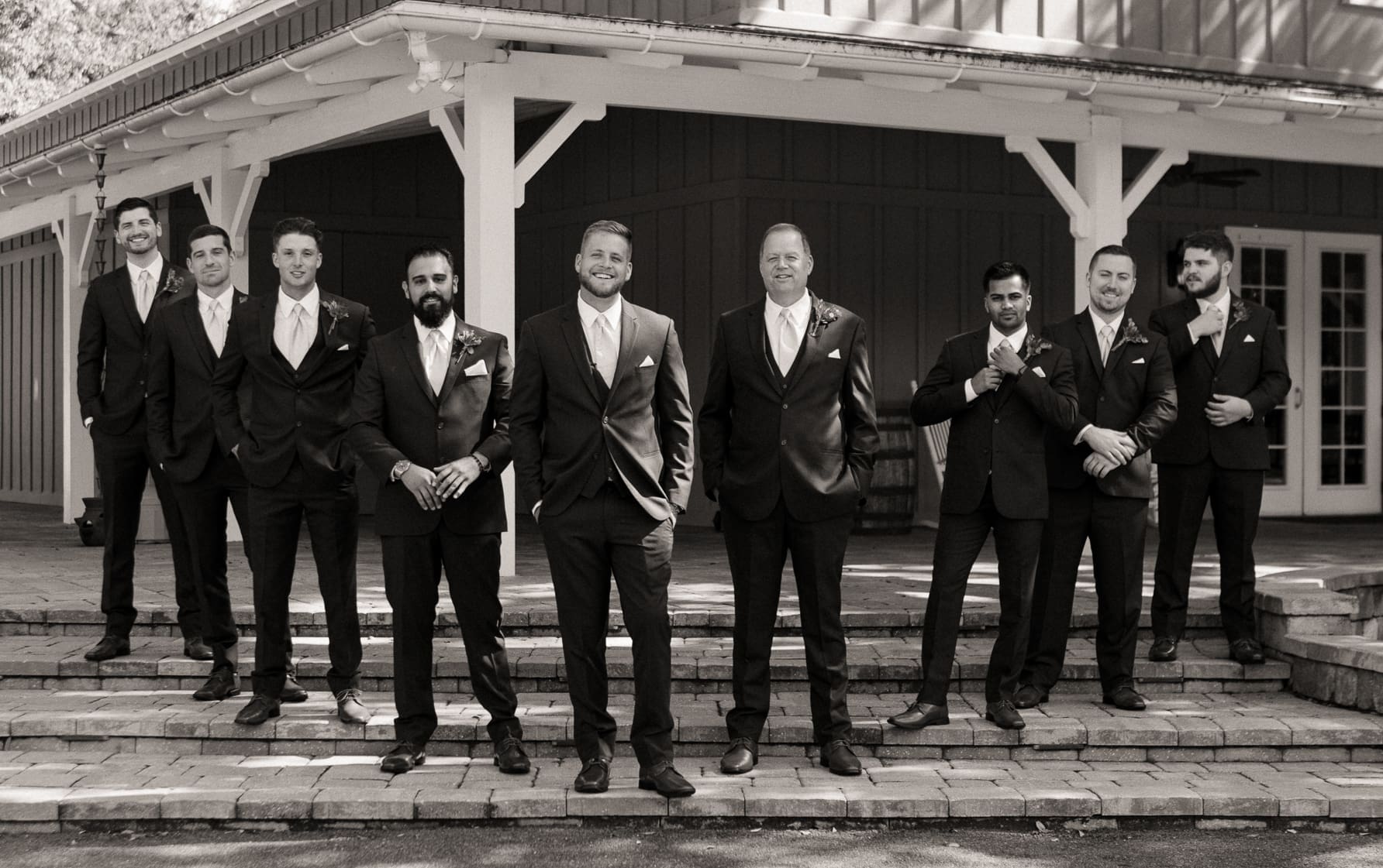Groomsmen and family members smiling together, black and white wedding photo. 