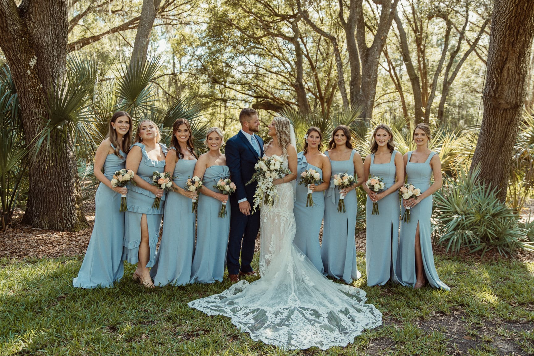 Meredith and Ryan with the full bridal party in dusty blue dresses at Bowing Oaks. 
