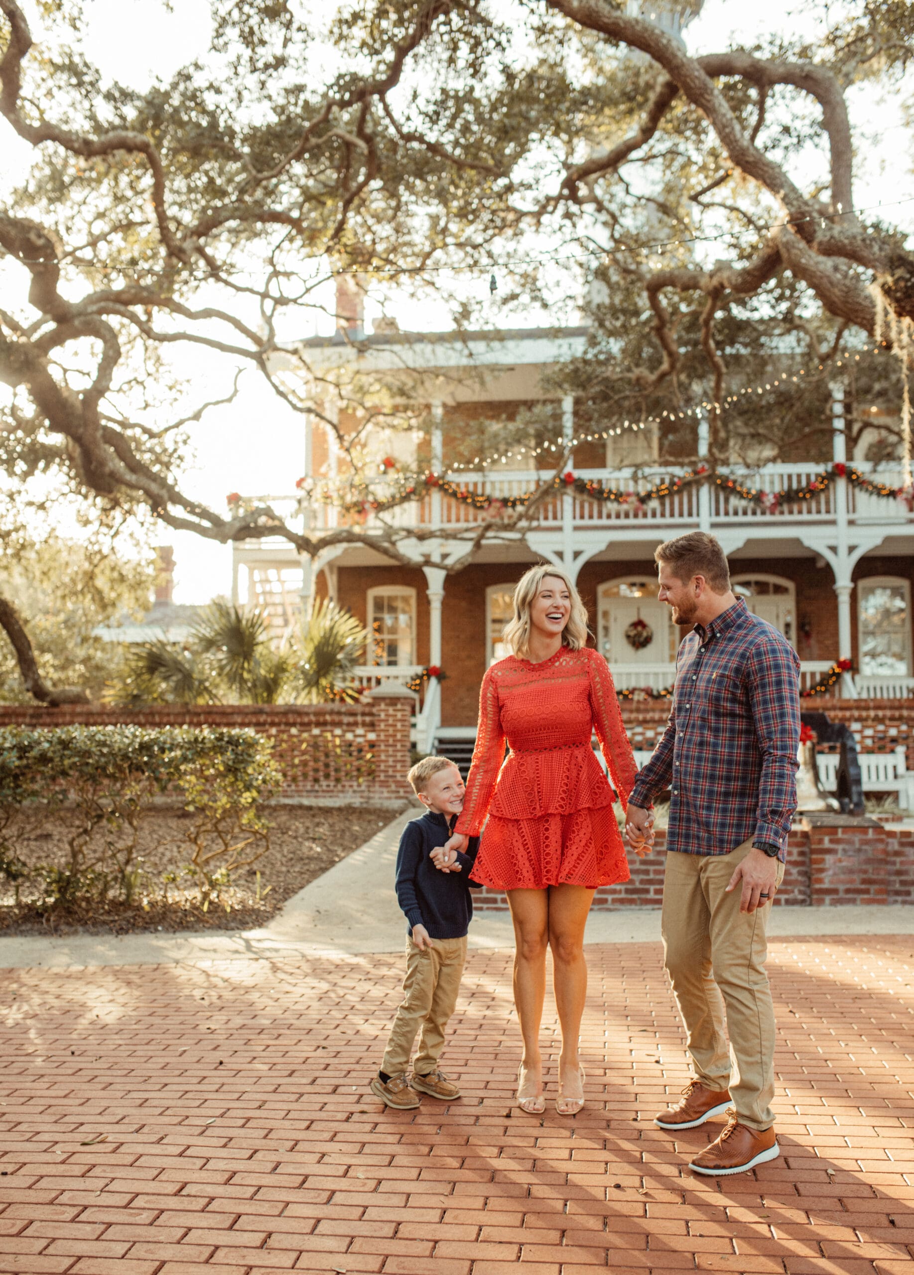 Family holding hands in front of the Christmas-decorated keeper's house at the St. Augustine Lighthouse