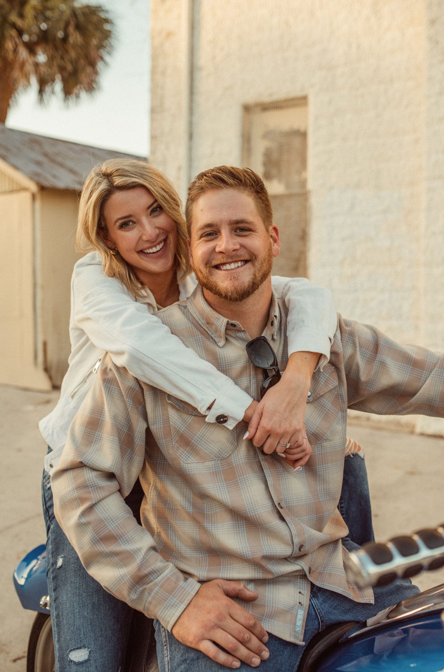 Smiling couple on a motorcycle in downtown St. Augustine, her arms wrapped around him