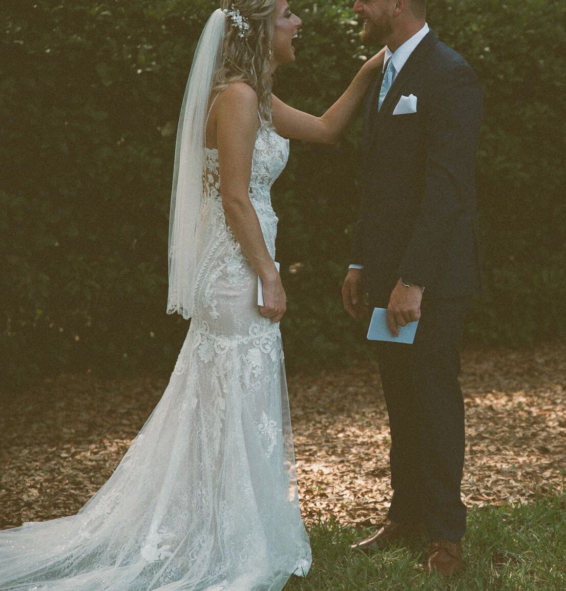 Bride laughing with her hand on the groom's shoulder during their first look, captured on color film.