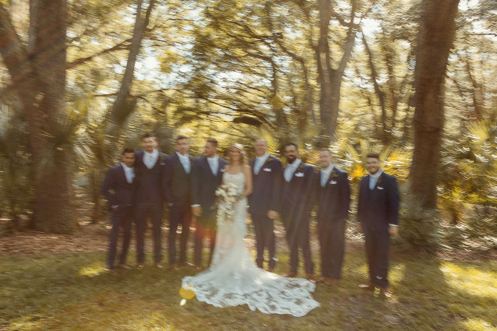 Bride with groomsmen among golden trees, with soft film motion and warmth.