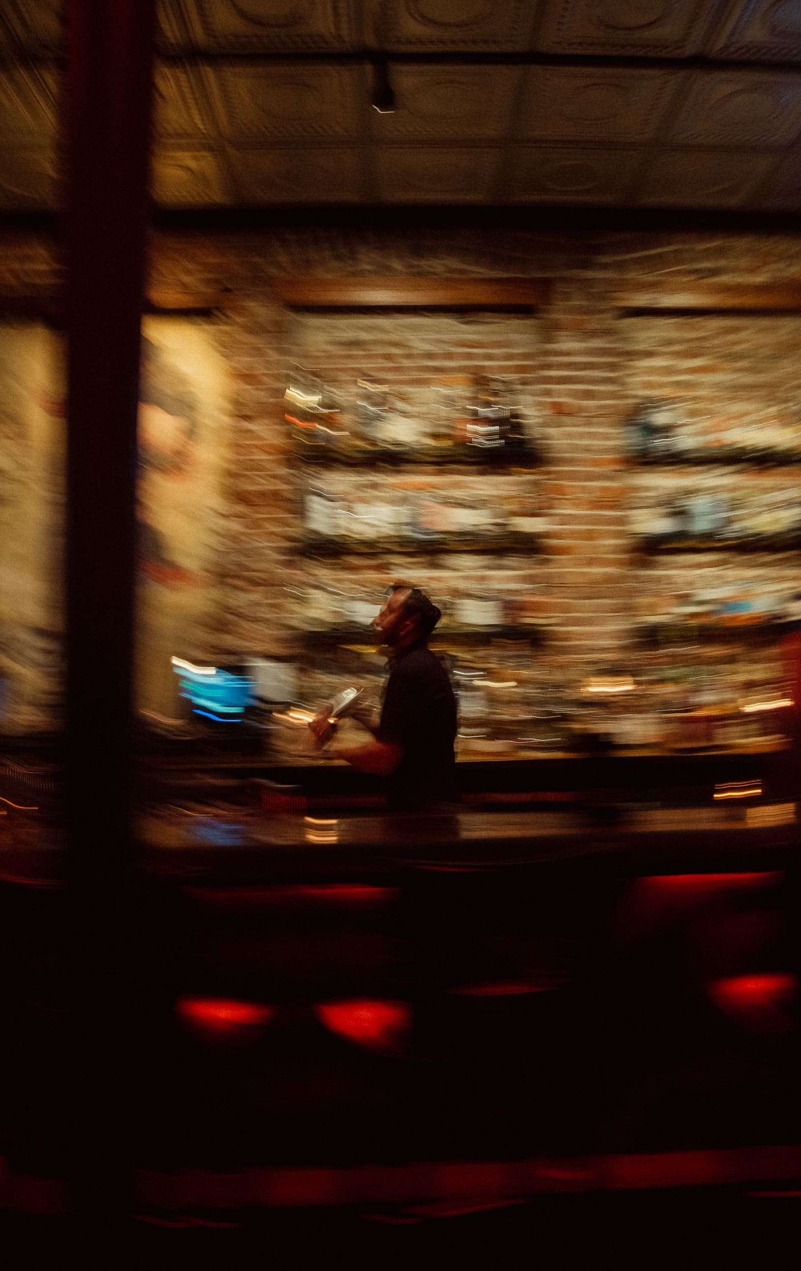 Motion-blurred view of the glowing backbar and bartender at Dos Gatos in downtown Jacksonville