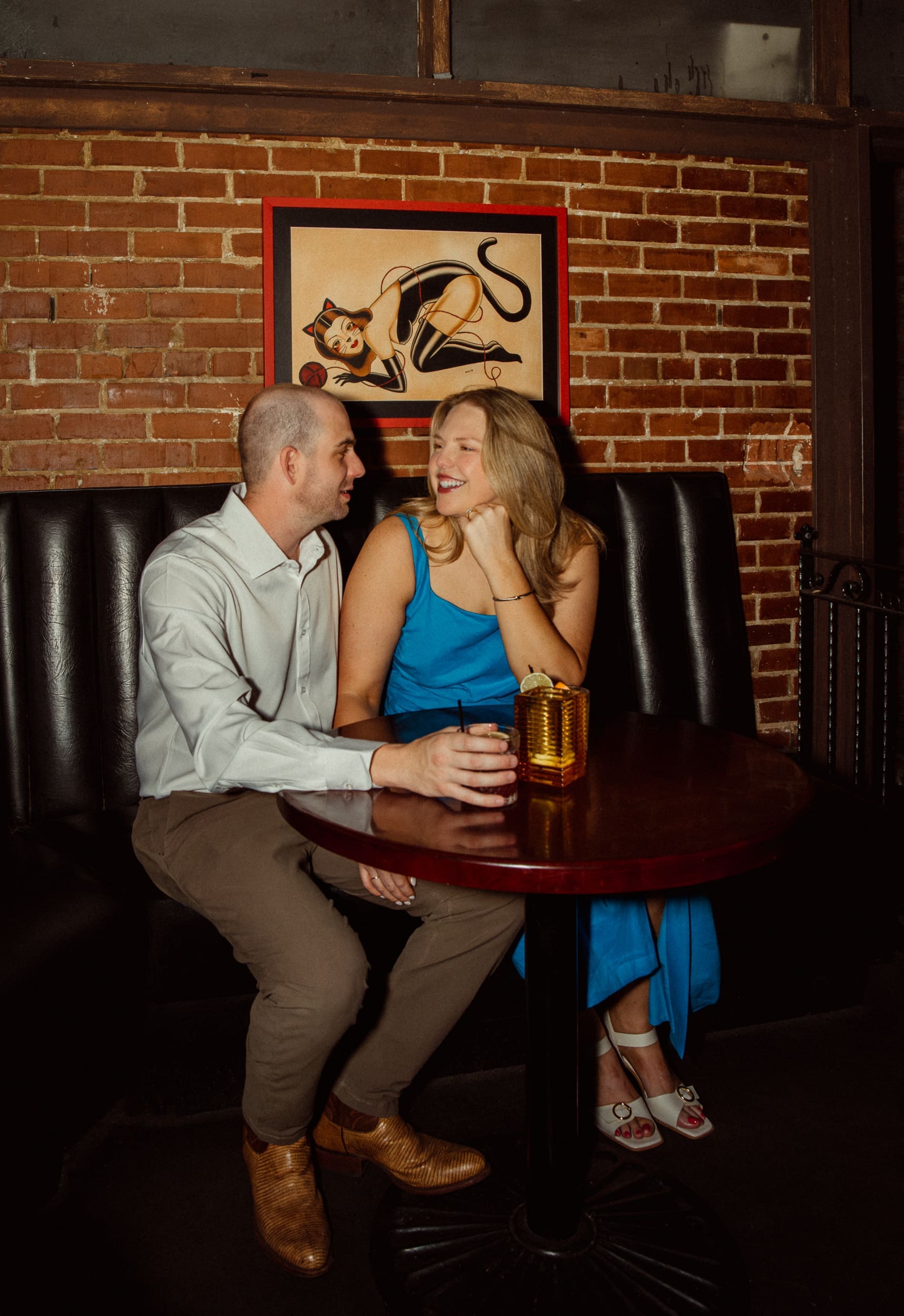 20. Woman resting her chin on her hand and laughing with her fiancé in a booth at Dos Gatos in Jacksonville